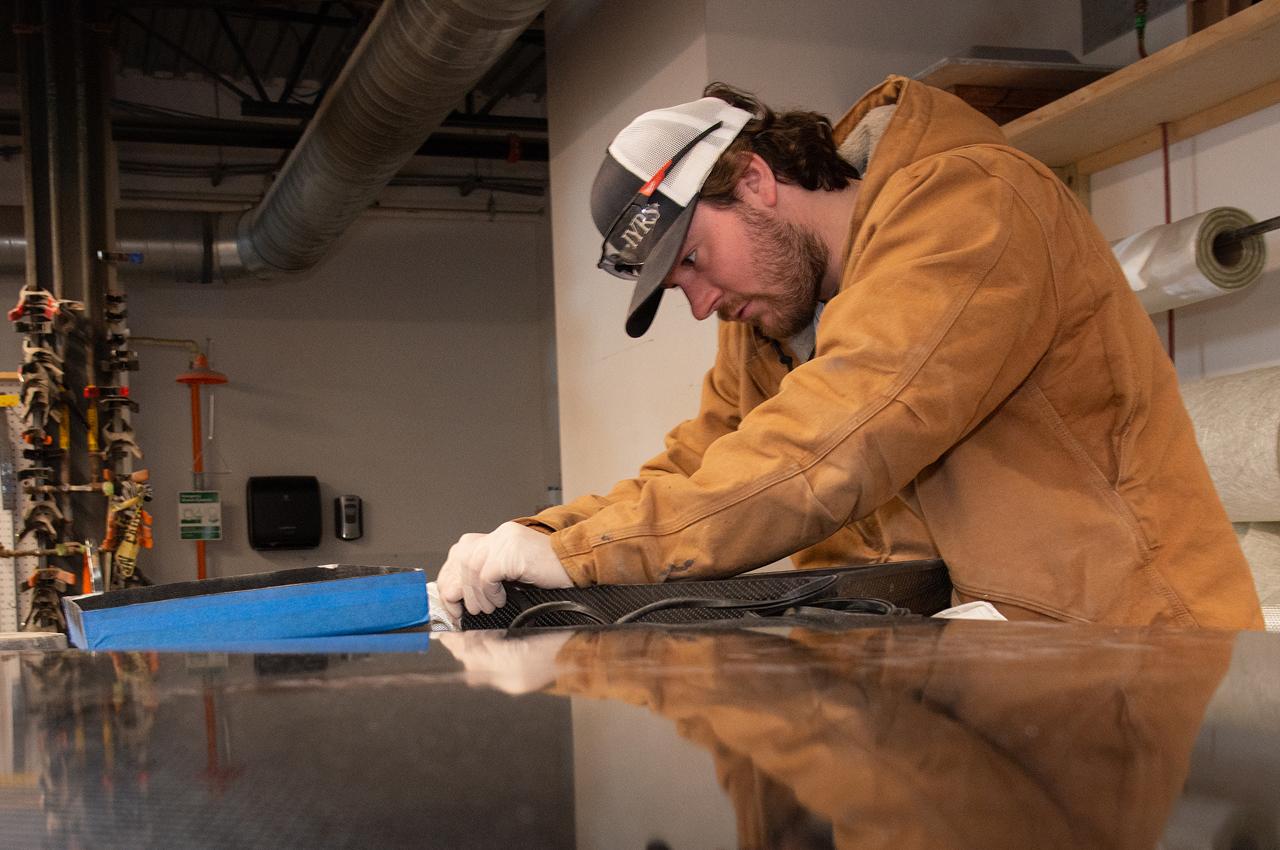 Worker in protective gear carefully working on a composite material.