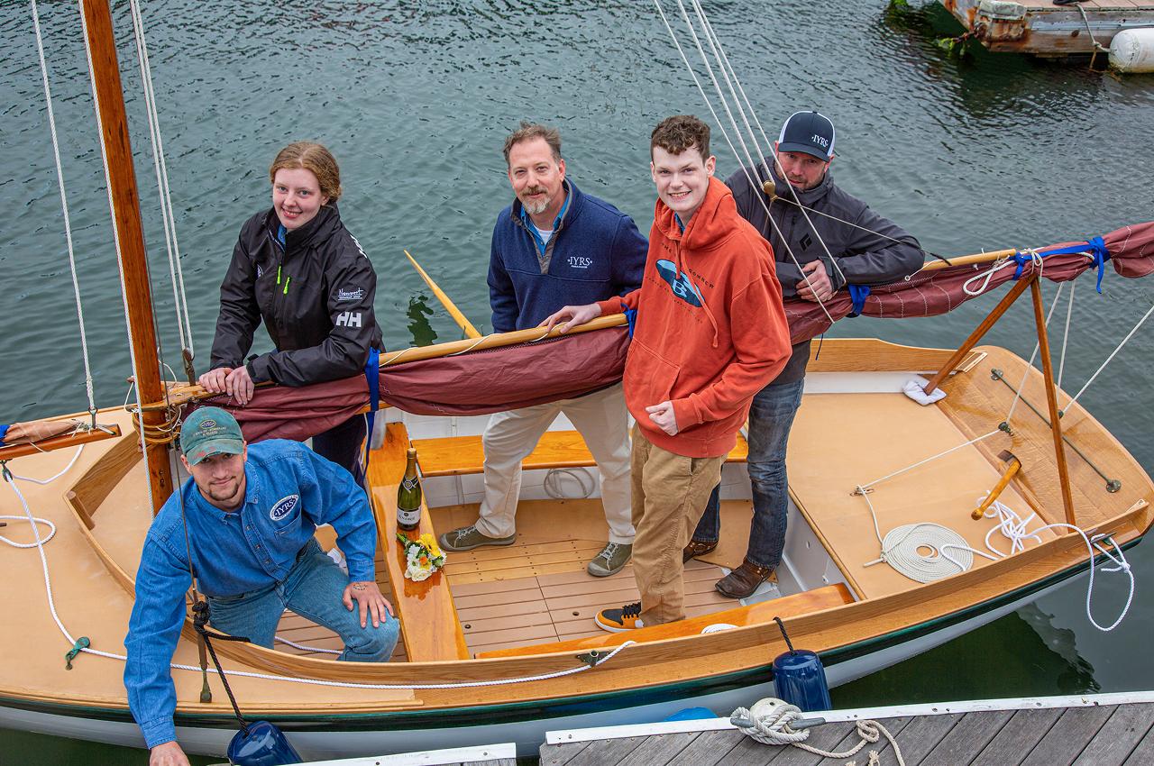Group on a wooden sailboat, preparing for launch.