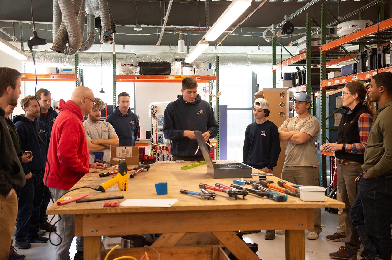 Instructor leading a hands-on lesson in a workshop surrounded by tools.